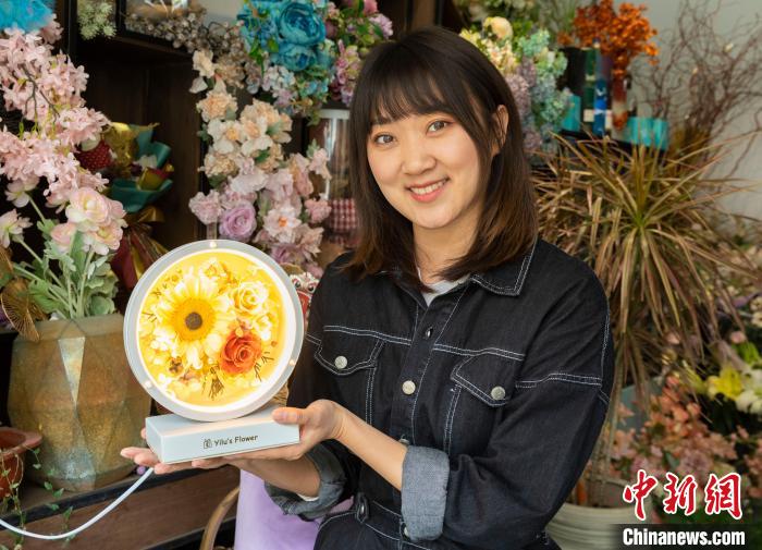 马媛展示她制作的点缀有永生花的台灯。 杨迪 摄