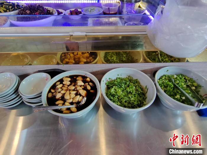 食客在煮好的面上浇上卤汁，并配以葱花、香菜等，再滴上几滴山西老陈醋，一碗热腾腾的刀削面就这样出炉。 高雨晴 摄