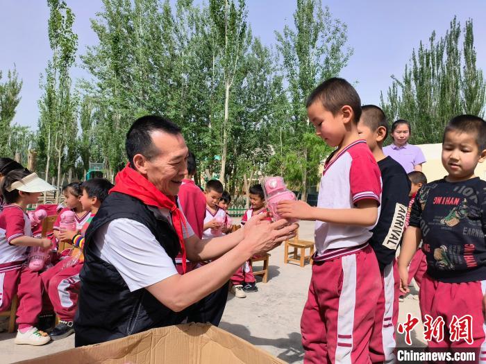 退伍老兵练志强为孩子们买来水杯、作业本等学习生活用品，作为15周年校庆礼物。 李伶 摄